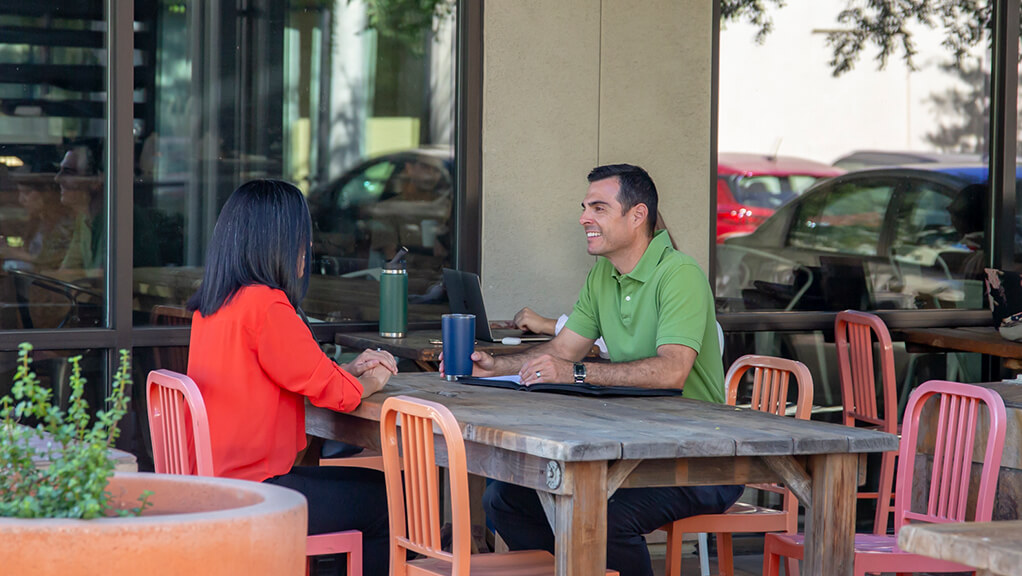 johnthan and woman discussing business outside a coffee shop